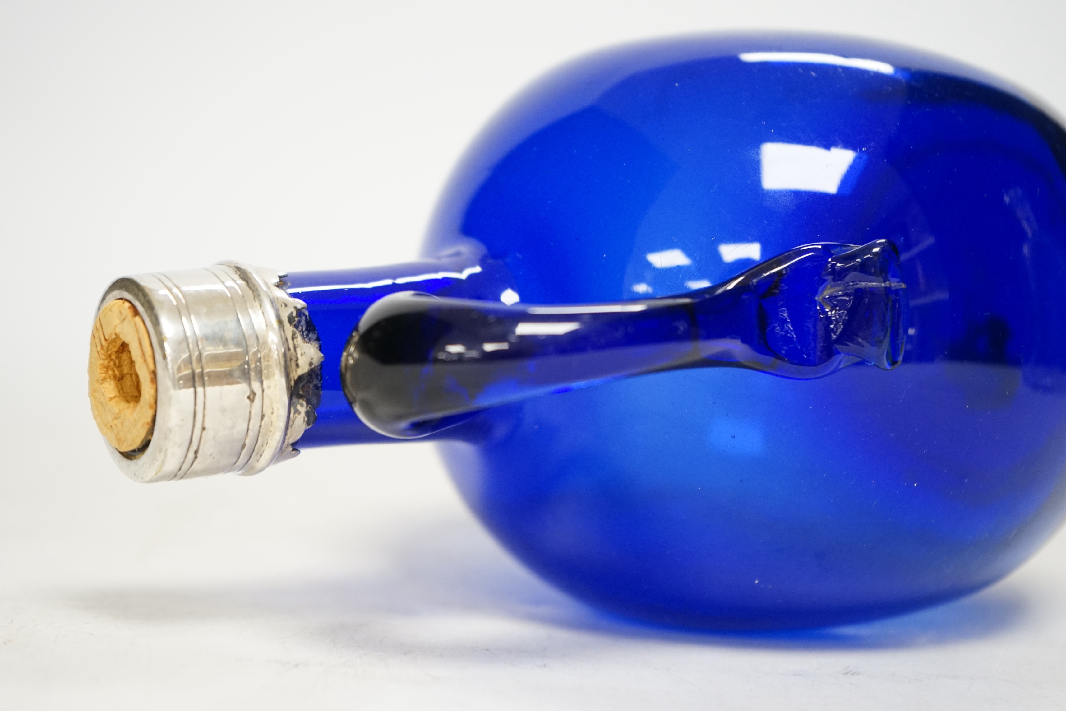 A silver mounted wheel engraved glass decanter and stopper and a white metal mounted Bristol blue decanter (2) tallest 23cm